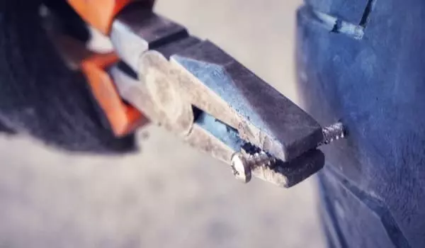 Garagiste effectuant la réparation d'une crevaison sur un pneu d'une moto ou d'un scooter